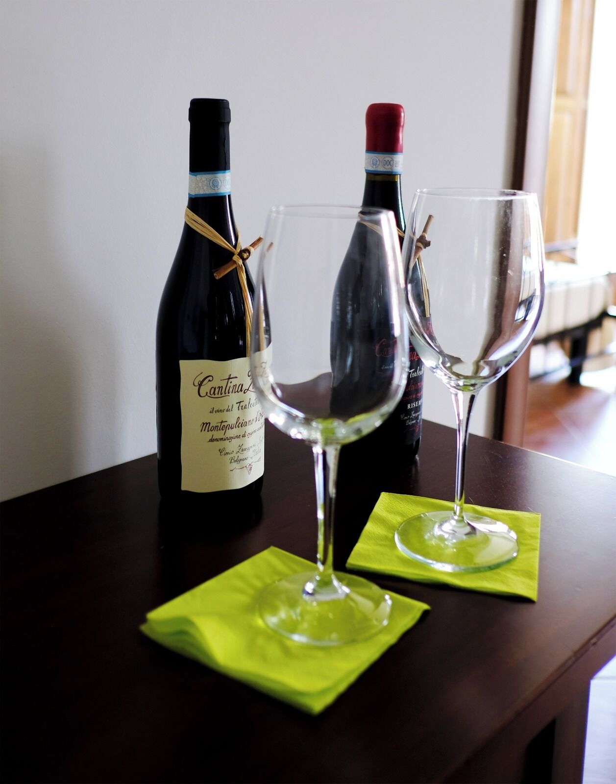 Una botella de vino y dos copas de vino vacías sobre una mesa.