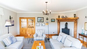 A living room with a sofa set, a coffee table, a fireplace, and a wooden door. - Traditional Cottage in Waterville on the Wild Atlantic Way (Waterville)