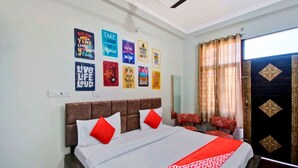 A hotel room with a bed, red pillows, a red bedspread, and motivational posters on the wall. - Hotel Shree Kanha (Jaipur)