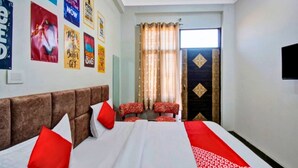 A hotel room with a bed, two red chairs, a TV, and motivational posters on the wall. - Hotel Shree Kanha (Jaipur)