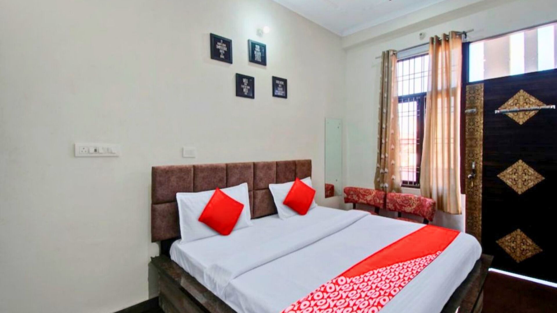 A hotel room with a bed, a window with curtains, and a door with a decorative design.