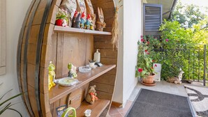A wooden barrel shelf with figurines and a teddy bear, a potted plant, and a small table with a mat.