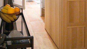 Um corredor com uma porta de madeira, uma cesta de frutas e uma televisão na parede.