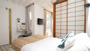 A bedroom with a bed, a TV, a shelf with toiletries, and a sliding door. - 21-Studio for 2 People-Central-Le Marais-Paris 4th (Paris)