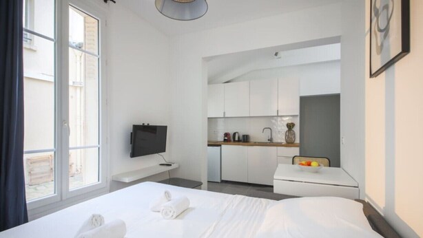 A hotel room with a bed, a TV, a kitchenette, and a window. - 5#Studio#2 People#Paris 15#Retail#AC (Paris)