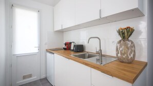 A compact kitchen with white cabinets, a wooden countertop, a sink, a kettle, a toaster, and a vase with flowers. - 5#Studio#2 People#Paris 15#Retail#AC (Paris)
