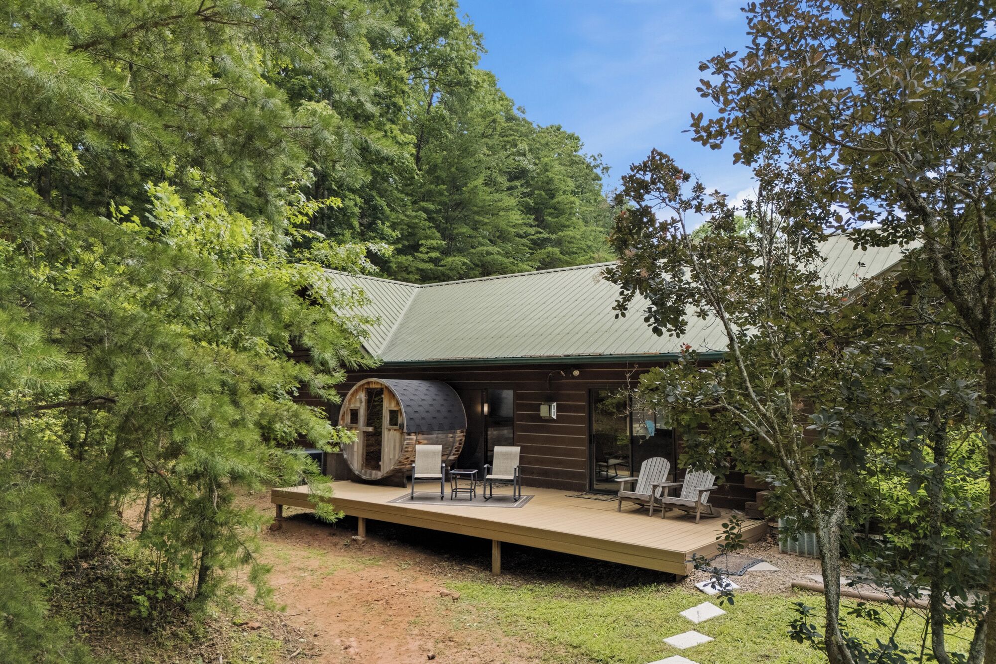 Eine Hütte mit einer Terrasse, Sitzgelegenheit im Freien und einem großen Fass.