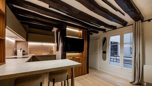 A modern kitchen with a bar area, wooden beams, and a large window. - Studio for 2 People #Île Saint-Louis #Along the Seine, Near Notre Dame (Paris)
