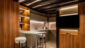 A compact kitchen with wooden accents, a built-in TV, and a bar stool. - Studio for 2 People #Île Saint-Louis #Along the Seine, Near Notre Dame (Paris)