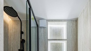 A modern bathroom with a glass shower enclosure, a toilet, and a wall-mounted light fixture. - Studio for 2 People #Île Saint-Louis #Along the Seine, Near Notre Dame (Paris)