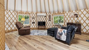 Ein gemütliches Interieur mit einer Couch, einem Sessel, einem Fernseher und einem kleinen Tisch.