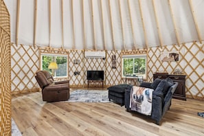 Ein gemütliches Interieur mit einer Couch, einem Sessel, einem Fernseher und einem kleinen Tisch.