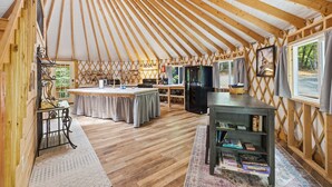 Una yurta con una zona de cocina, una mesa de comedor y una estantería.