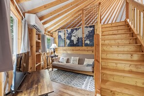 Ein Holzinnenraum mit einer Treppe, einem Sofa, einem Tisch und einer Weltkarte an der Wand.