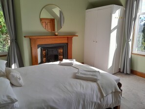 Quarto com cama, lareira, guarda-roupa e espelho.