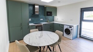 A compact kitchen with a round table, built-in appliances, and a washing machine. - Modern Studio Apartment in the Heart of Cahersiveen (Cahersiveen)