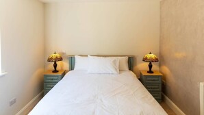A bedroom with a bed, two bedside tables, and two lamps. - Modern Studio Apartment in the Heart of Cahersiveen (Cahersiveen)