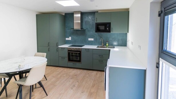 A modern kitchen with a dining area, built-in appliances, and a window. - Modern Studio Apartment in the Heart of Cahersiveen (Cahersiveen)