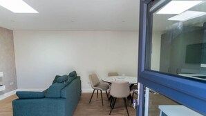 A modern interior with a teal sofa, a round dining table, and chairs. - Modern Studio Apartment in the Heart of Cahersiveen (Cahersiveen)