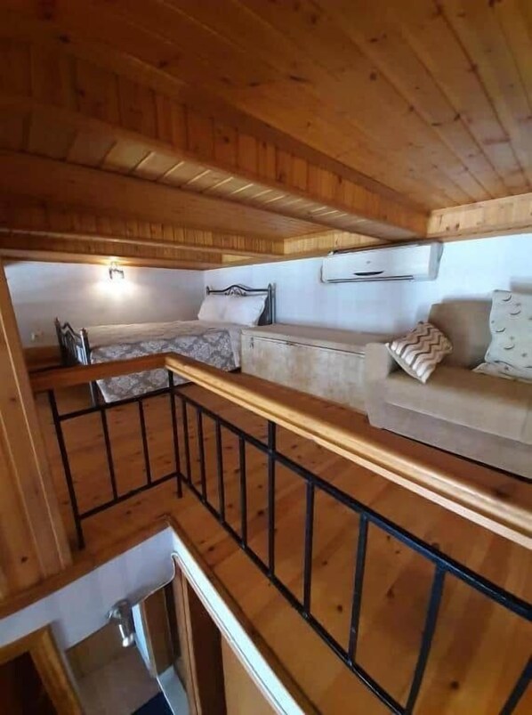 Un interior de madera con un sofá, una cama y una barandilla.