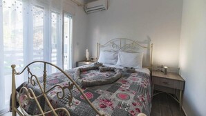 Ein Schlafzimmer mit einem Bett, einem Nachttisch, einer Klimaanlage und einem Fenster mit Vorhängen.