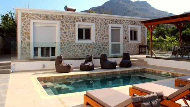 Ein Gebäude aus Stein mit Pool, Außenbereich und Bergblick.