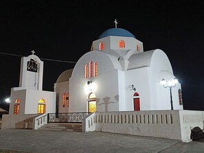 A white church with a blue dome, a bell tower, and lit windows. - Oropos Relax View (Oropos)