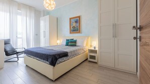 A bedroom with a bed, bedside tables, a chair, a wardrobe, and a painting on the wall. - Regina Margherita by Wonderful Italy (Torino)