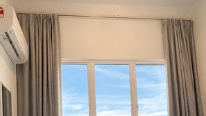 A hotel room with a bed, a window with curtains, an air conditioning unit, and a view of the outdoors. - Spacious 3-bedroom neighborhood apartment with AC in Langkawi (Langkawi)