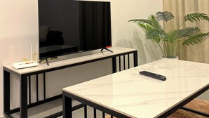 A modern living room with a flat-screen TV, a coffee table, and a potted plant. - Spacious 3-bedroom neighborhood apartment with AC in Langkawi (Langkawi)