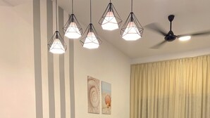 A dining area with a table, chairs, and hanging lights. - Spacious 3-bedroom neighborhood apartment with AC in Langkawi (Langkawi)