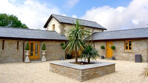 A stone building with a courtyard, a yellow door, and a large plant in the center. - Valley View (Ross-on-Wye)