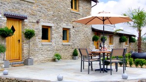 A stone building with a patio area featuring outdoor furniture and potted plants. - Valley View (Ross-on-Wye)