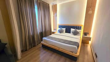 A modern bedroom with a large bed, wooden flooring, and a ceiling fan.