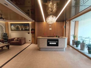 A reception desk labeled 'TOWNHOUSE' with a chandelier, a sofa, and a painting on the wall.