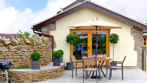 A patio with stone flooring, a table with chairs, and a grill. - Howle Hideaway (Ross-on-Wye)