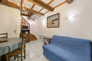 Ein Zimmer mit Esstisch, Stühlen, einem blauen Sofa, einem Gemälde und einer Treppe, die zu einem anderen Raum führt.