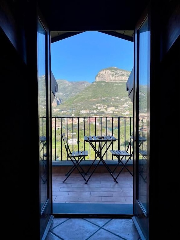 Un balcón con mesa y sillas, vista a la montaña y cielo despejado.