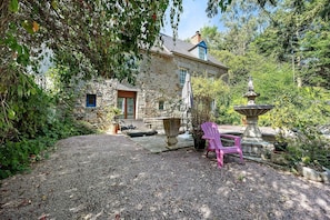 A stone house with a garden, a fountain, and outdoor seating.