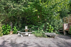 A garden with a stone bench, a bird feeder, and a Buddha statue. - Charming 17th-Century Holiday Home “Gîte Le Mont Saint Michel” with Wi-Fi (Bacilly)