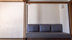 A room with a wooden ceiling, a grey sofa with cushions, and a wooden floor.