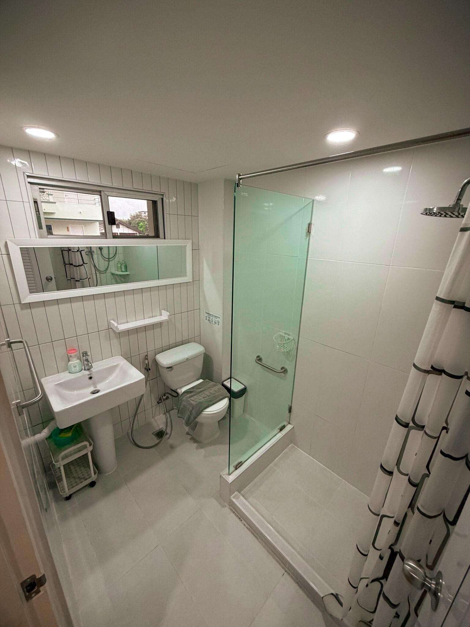 A modern bathroom with a glass-enclosed shower, a toilet, a sink, and a mirror above the sink.