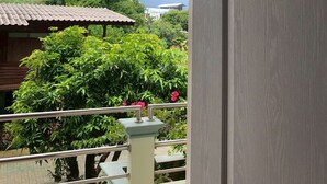Uma varanda com vista para uma paisagem verde, um edifício com telhado de azulejos e um céu nublado.