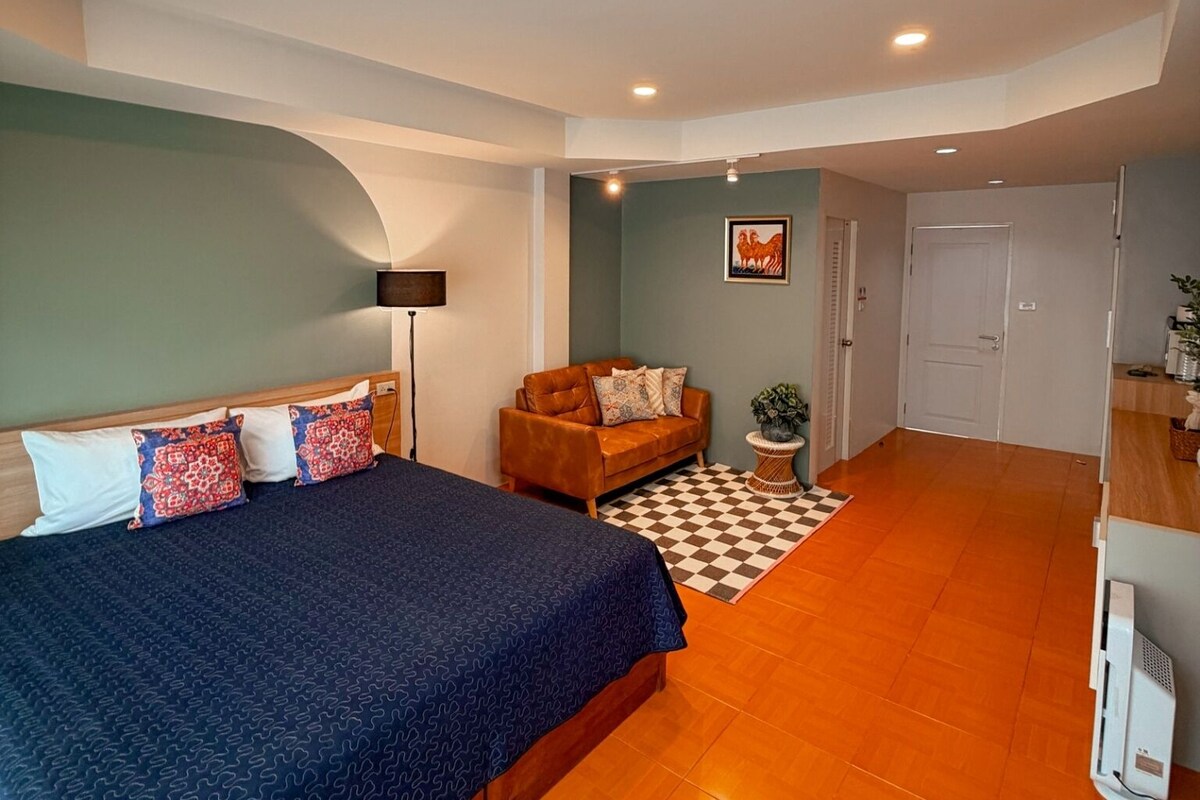 Une chambre à coucher avec un lit, un canapé, une lampe et un tapis à carreaux.
