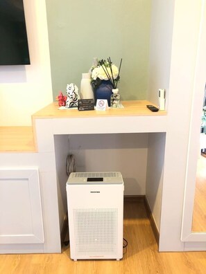 Ein Zimmer mit Schreibtisch, einem Kashiwa Luftreiniger, einer Vase mit Blumen und einem Teddybär.