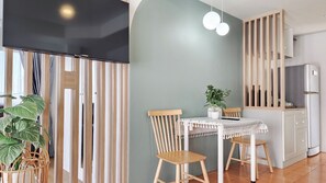 Eine moderne Küche mit Holdekor, einem Kühlschrank, einem Esstisch mit Stühlen und einer Zimmerpflanze.