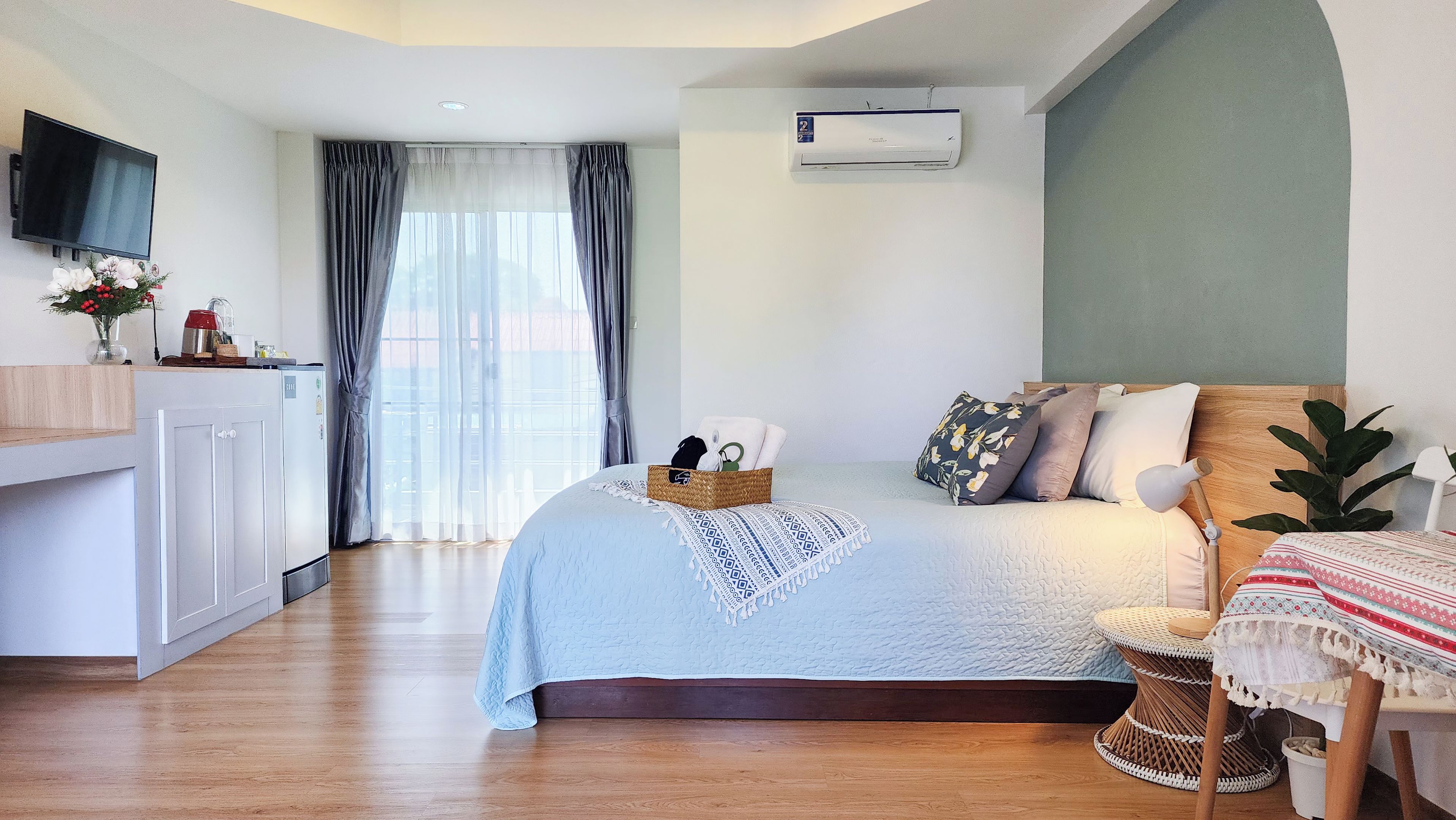 A bedroom with a bed, bedside table, and a TV mounted on the wall.