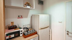 Cozinha compacta com geladeira, micro-ondas e cafeteira na bancada.
