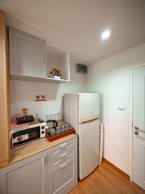 Una cocina compacta con refrigerador, microondas y cafetera sobre la encimera.