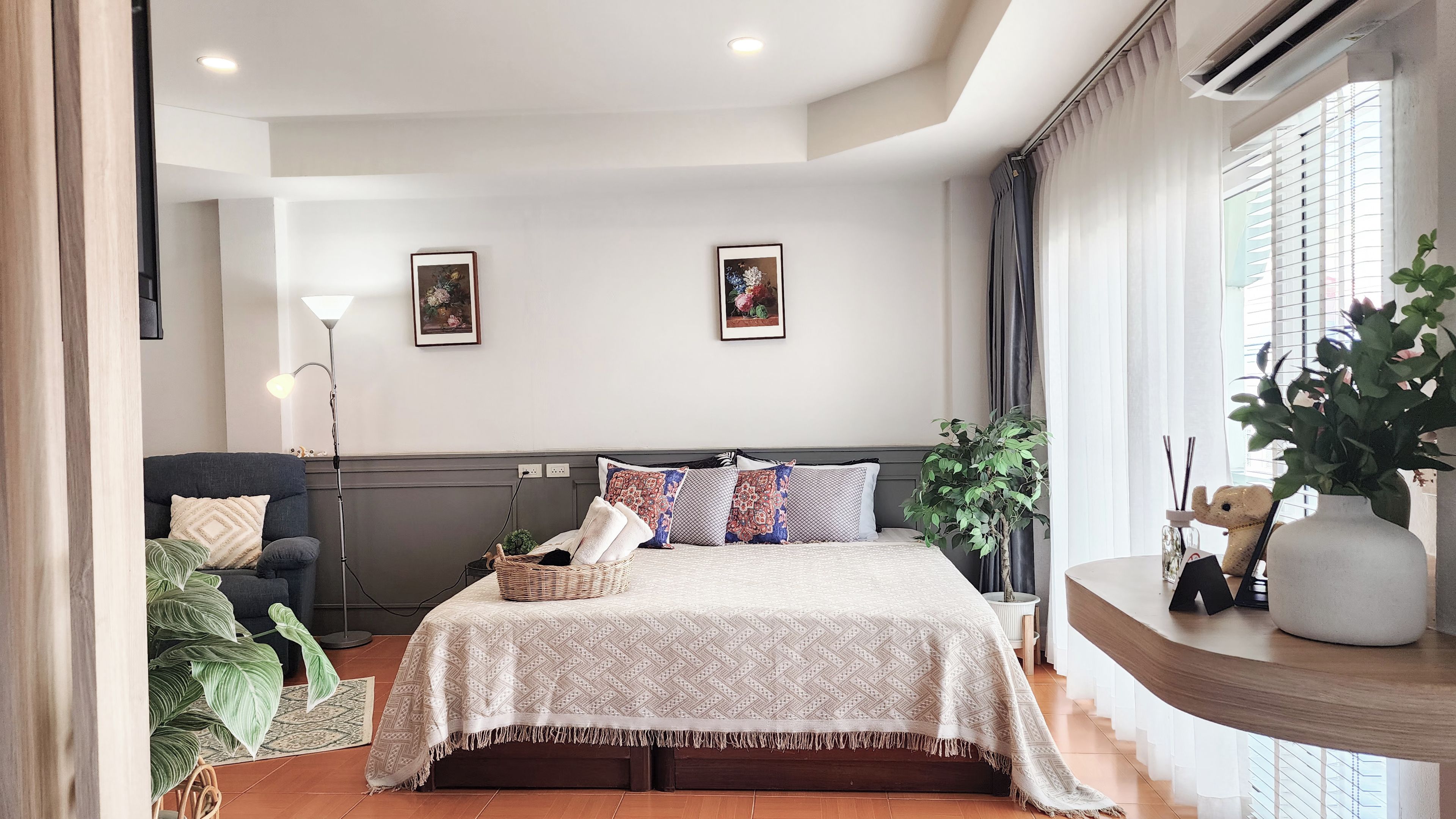 Une chambre à coucher avec un lit, une chaise, une lampe et une plante en pot.